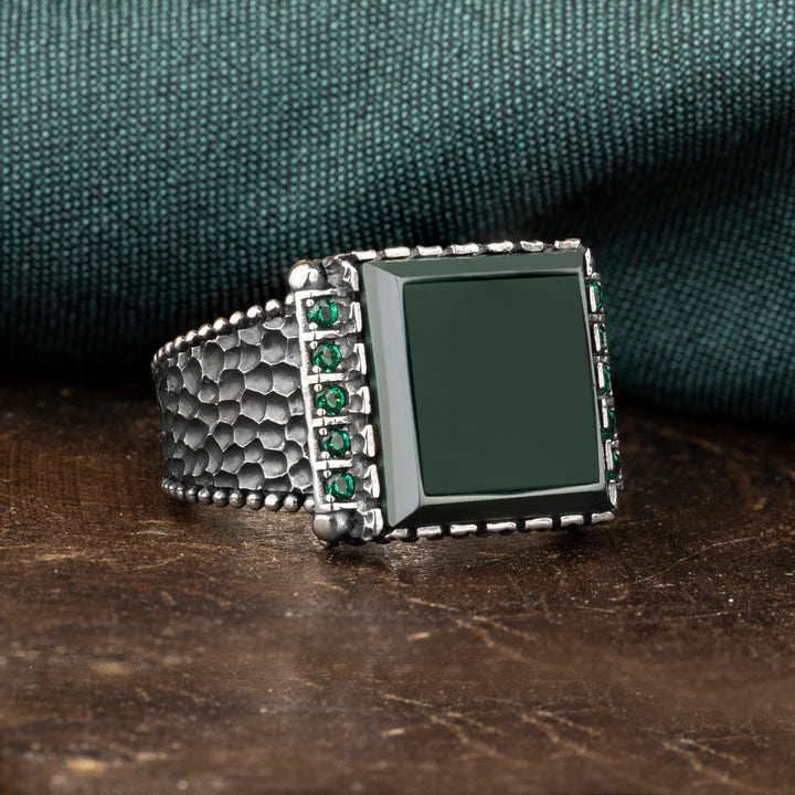 Green agate square stone silver ring  with green zircone stones on two sides on the brown ground and green silk background 
